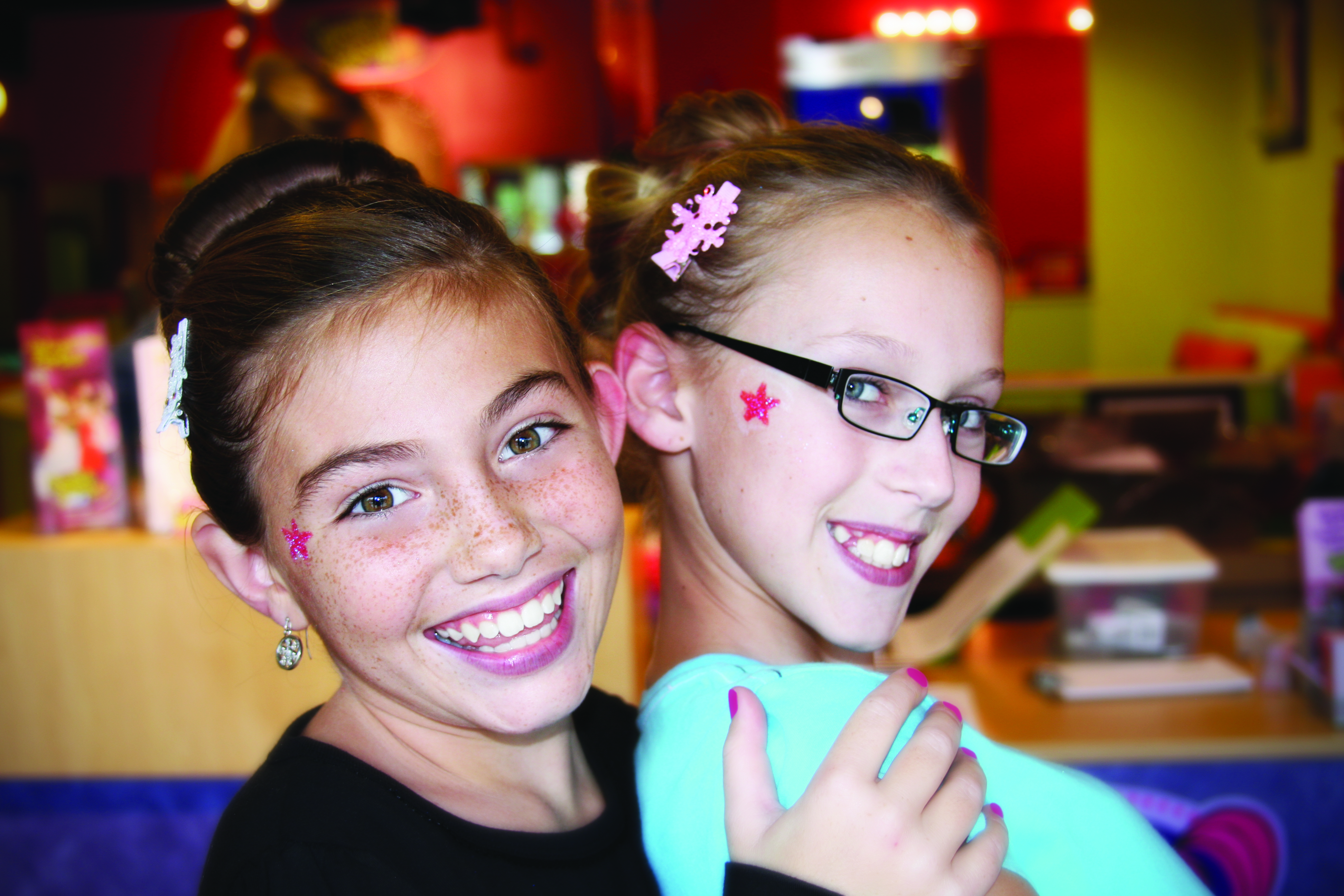 Two girls smiling for photo in kids hair salon in Fall Creek