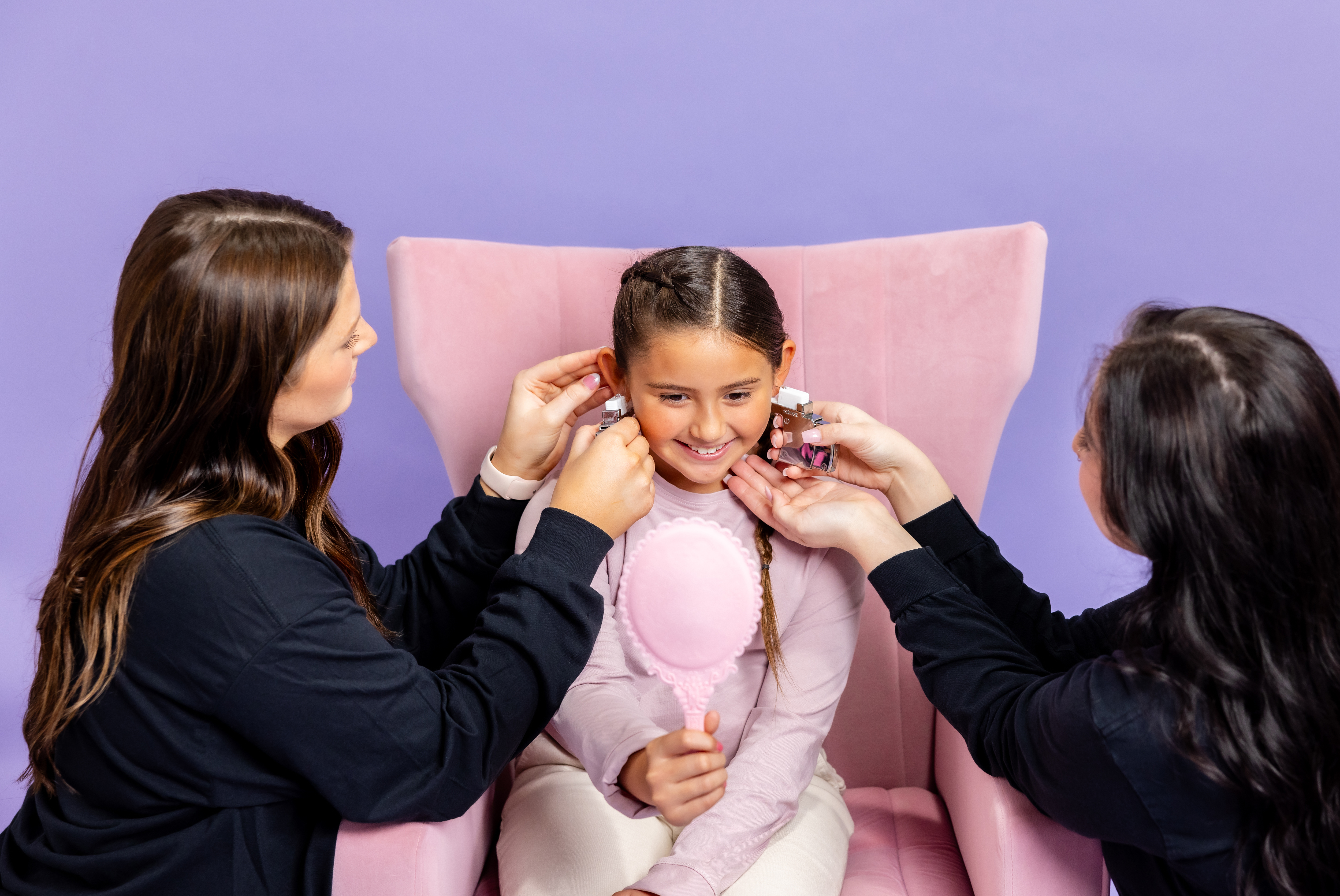 girl looking in the mirror at her pierced ears